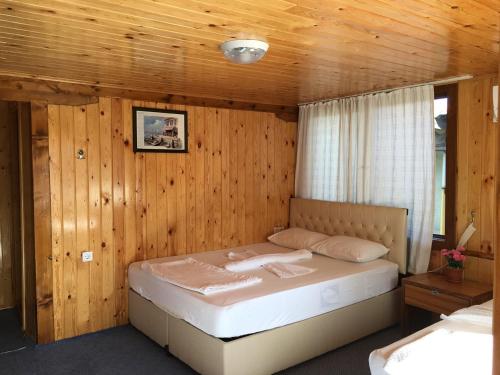 1 dormitorio con 1 cama en una pared de madera en Gonul Pansiyon en Kaleucagız