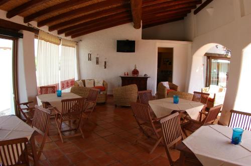 un ristorante con tavoli, sedie e un divano di Santa Maria Resort a Orosei