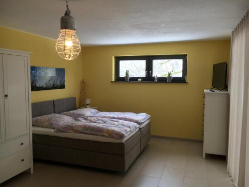 a bedroom with a bed and a television and a chandelier at Ferienhaus HAAGALM in Primstal