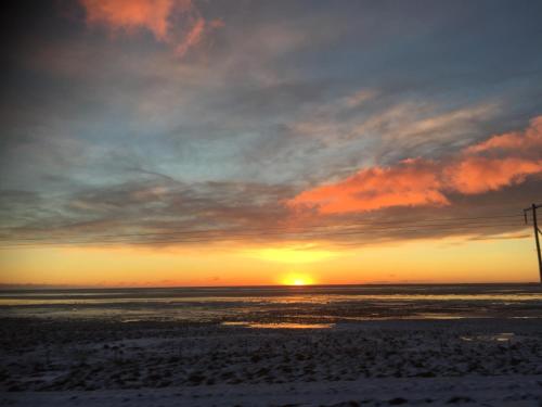 a sunset on the beach with the sun setting at Hrafnavellir Guest House in Hrafnavellir