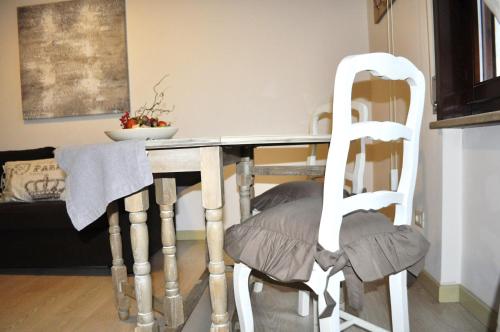 een eettafel met twee witte stoelen in een kamer bij Appartamento Romantico in Cremona