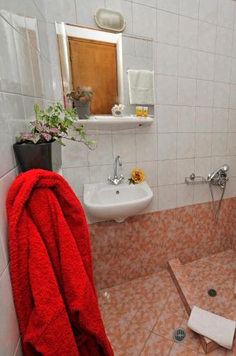 un bagno con un asciugamano rosso appeso a un lavandino di Gorgiani a Spercheiada