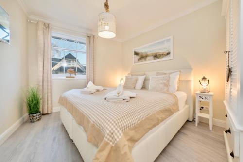 a white bedroom with a large bed with a window at Villa Strandblick 9 in Zingst