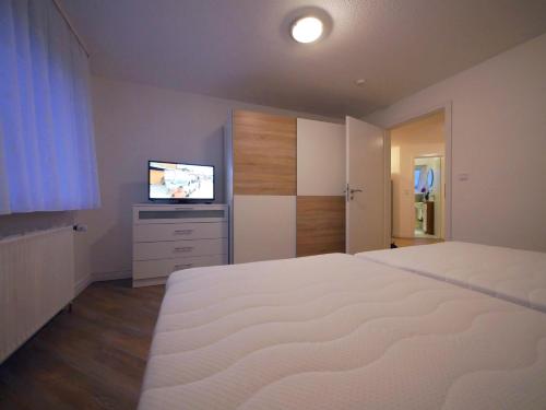 a bedroom with a large white bed and a television at Ferienwohnung Hamburg / Lüneburg in Scharmbeck