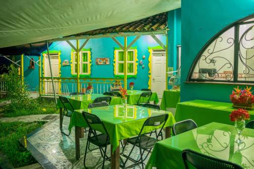 a restaurant with green tables and chairs in front of a blue wall at Finca Azulinas in La Tebaida