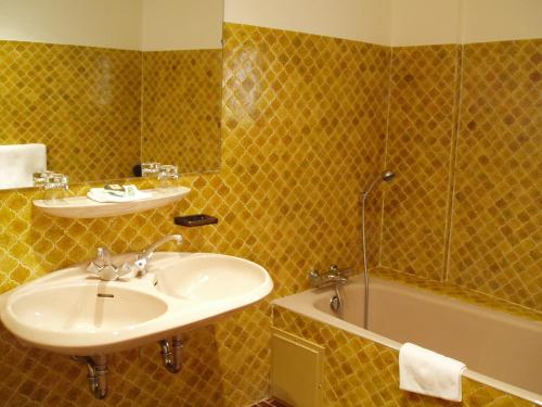 a bathroom with a sink and a bath tub at Logis Hôtel Les Hospitaliers in Le Poët-Laval