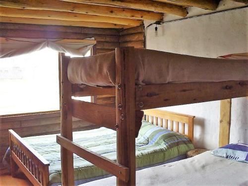 Litera de madera en habitación con ventana en Hostería de Montaña los Duendes del Volcán en Caviahue