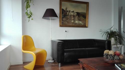 a living room with a black leather couch and a table at TOLETUM low cost LOFTS diáfanos o 2dormitorios PARKING Municipal Gratis al aire libre a 100m in Toledo