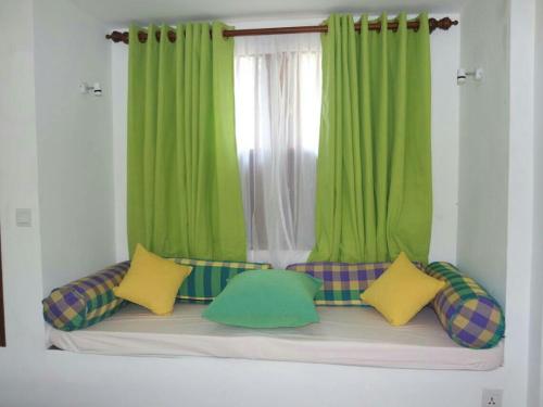 a couch with green curtains and pillows in front of a window at Blue Water hikkaduwa in Hikkaduwa