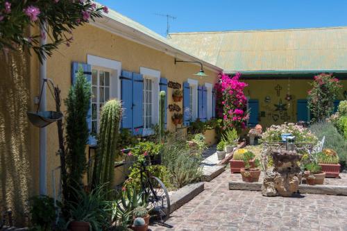 a garden with cacti and flowers on a building at Somerset Stables in Graaff-Reinet