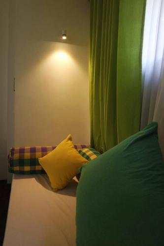 a bed with a yellow pillow and a green curtain at Blue Water hikkaduwa in Hikkaduwa