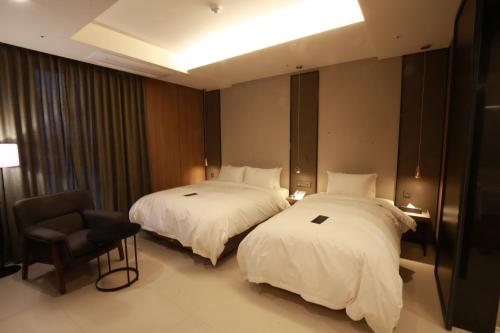 a hotel room with two beds and a chair at Hotel East9 in Gangneung