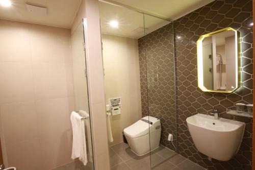a bathroom with a toilet and a sink and a mirror at Hotel East9 in Gangneung