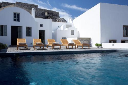 a group of chairs sitting next to a swimming pool at Villa Fabrica Santorini in Pyrgos