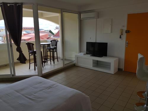 1 dormitorio con 1 cama, TV y balcón en Hello Guyane 1 - Appartement de Luxe, 5 étoiles, en Cayenne