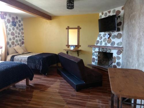 ein Wohnzimmer mit einem Bett und einem Kamin in der Unterkunft Hotel Posada El Camino in Chignahuapan