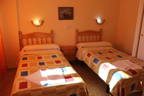 two beds in a room with orange walls at Apartamentos Congo in El Campello