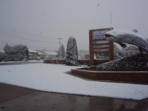 a persons hand is covered in snow next to a sign at Big Trout Motel in Oberon