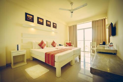 Un dormitorio con una gran cama blanca y una ventana en Beacon Beach Hotel Negombo en Negombo