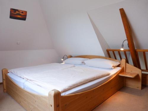 a wooden bed with white sheets and pillows in a room at Ferienwohnung Bi Elschen in Nebel