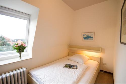 una piccola camera da letto con un letto con un libro sopra di Haus Therese Ferienwohnung *Feodora* (App.11) a Wittdün