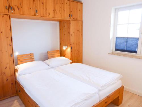 Schlafzimmer mit einem Holzbett mit weißer Bettwäsche in der Unterkunft Ferienwohnung *Reethuk* in Norddorf