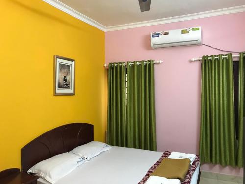 a bedroom with a bed and green curtains at Indraprastham Tourist Home in Kottayam