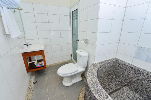 a bathroom with a toilet and a bath tub at Fu Yu Spring House in Baihe