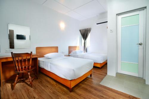 a bedroom with two beds and a desk and a chair at MG Hotel in Mersing
