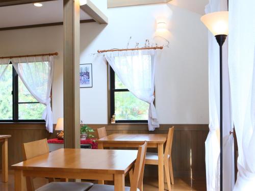a dining room with a table and chairs and windows at Anise Garden in Hakuba