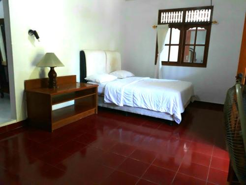 a bedroom with a bed and a desk and a window at G Saskara Homestay in Sanur