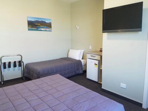 um quarto de hotel com duas camas e uma televisão de ecrã plano em Stumpers Hotel em Hokitika