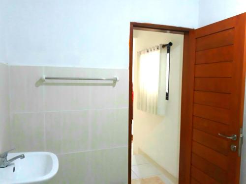 a bathroom with a sink and a toilet and a door at G Saskara Homestay in Sanur