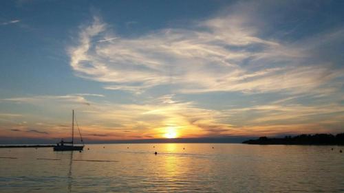 a boat on the water with a sunset in the background at Apartments Pepe in Novigrad Istria