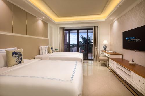 a hotel room with two beds and a flat screen tv at Wyndham Hainan Clearwater Bay Resort in Lingshui