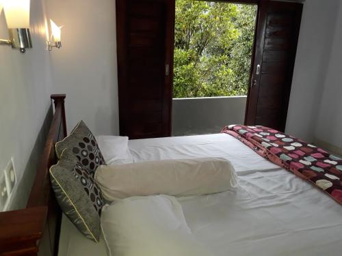 a bedroom with a white bed with a window at Sugi Gede Homestay in Singaraja