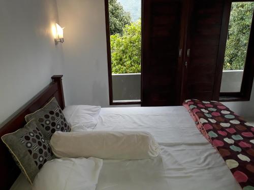 a bedroom with a white bed with two windows at Sugi Gede Homestay in Singaraja