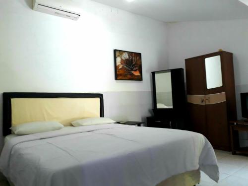 a bedroom with a large white bed and a mirror at G Saskara Homestay in Sanur