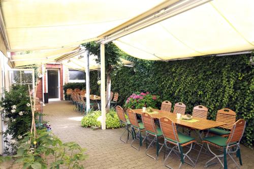 a patio with a table and chairs and a green wall at Hotel Kröger in Ennigerloh