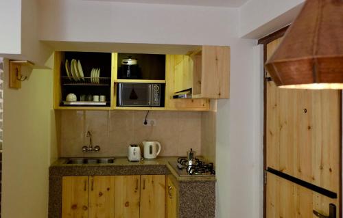 a small kitchen with wooden cabinets and a microwave at Hotel Timila in Pātan