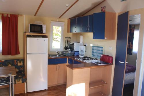 VerteillacにあるCamping du Pontisのキッチン(青いキャビネット、白い冷蔵庫付)