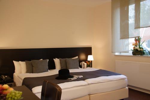 a hotel room with a bed with a hat on it at Hotel Bonjour in Bad Soden am Taunus