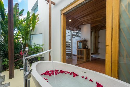 a bath tub with red flowers inside of a bathroom at White Sand Samui Resort in Lamai