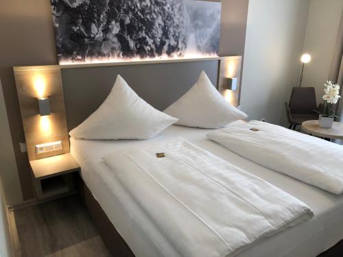 a large bed with white sheets and pillows on it at Hotel Traumblick in Cochem