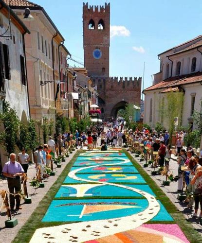 a crowd of people walking down a street with a mural at Novalesi Red House in Noale