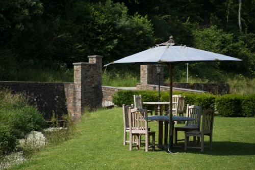 a table and chairs under an umbrella in a yard at Hotel Le Moulin Simonis in Laforêt