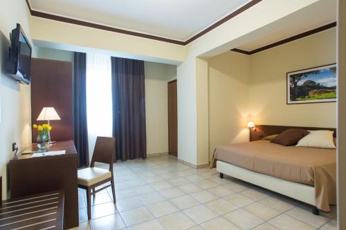 ein Hotelzimmer mit einem Bett, einem Schreibtisch und einem Zimmer in der Unterkunft Hotel Vittoria in Rosarno