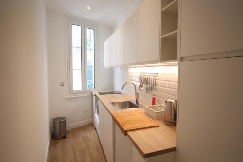 een keuken met witte kasten, een wastafel en een raam bij Appartement VALENTINE in Trouville-sur-Mer