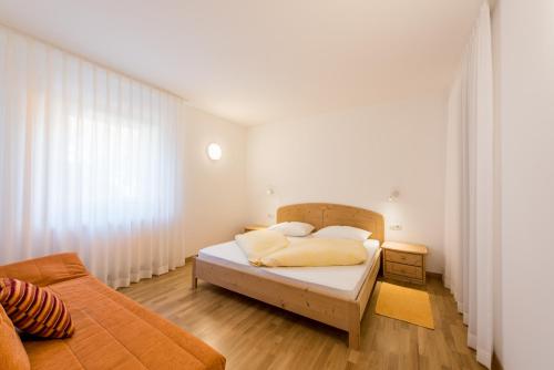 um quarto com uma cama com paredes brancas e pisos em madeira em Haus Gufler em Silandro