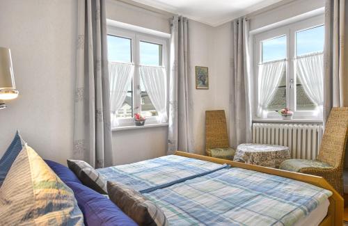 a bedroom with a bed and a chair and windows at Pension "Haus am Walde" Brodenbach, Mosel in Brodenbach
